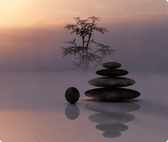 Zen stones stacked beside bamboo at sunset symbolizing balance and harmony
